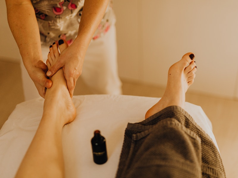 Crop therapist massaging foot of client
